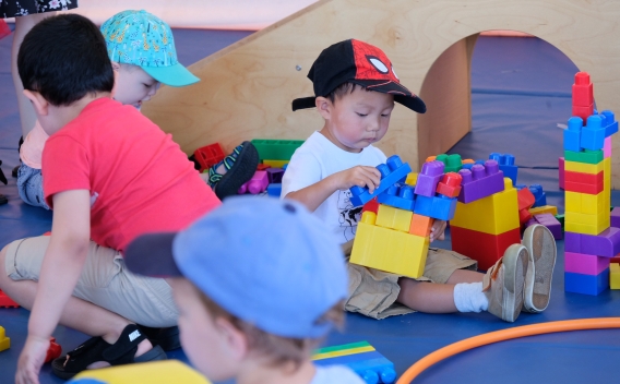 children playing with large blocks and other toys on play mat